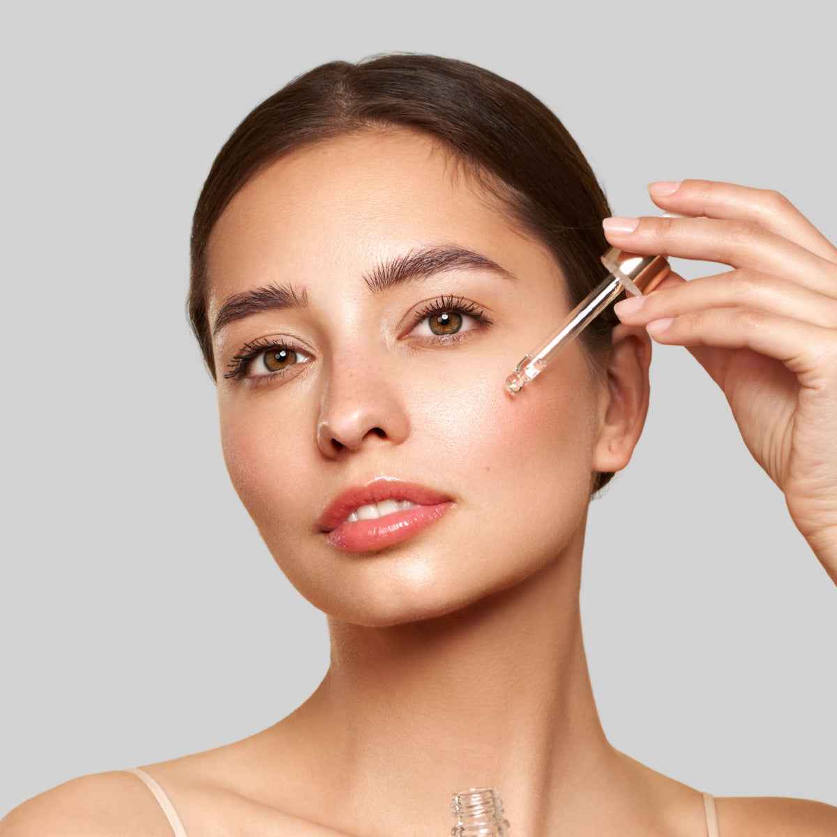 Femme appliquant quelques gouttes d’huile de graines de figue de barbarie sauvage bio sur son visage à l’aide d’une pipette, illustrant une routine beauté naturelle pour une peau douce, nourrie et lumineuse.